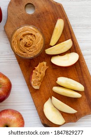 Raw Red Apples And Peanut Butter On A Rustic Wooden Board On A White Wooden Table, Overhead View. Flat Lay, From Above, Top View.