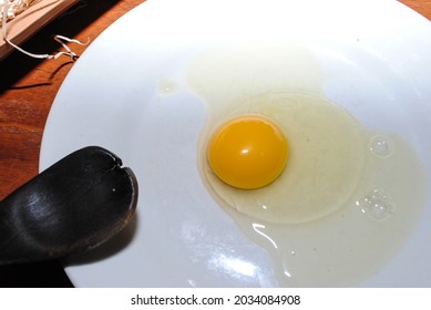 Raw Red Chicken Eggs On A Plate. You Can See The Tip Of A Wooden Spoon