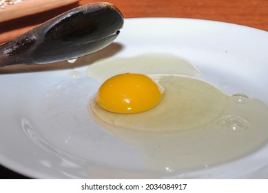 Raw Red Chicken Eggs On A Plate. You Can See The Tip Of A Wooden Spoon