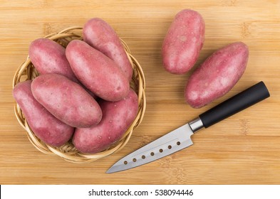 Raw red potato in wicker basket on bamboo cutting board and kitchen knife. Top view - Powered by Shutterstock