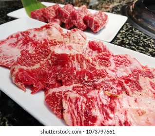 Raw red slice of Japanese kobe fresh beef on white plate in restaurant.