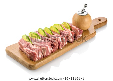 Raw rib eye or ribeye, a beef steak from the rib section with the bone removed, ready to be cooked. On a cutting board with lemon slices. Isolated on white background.