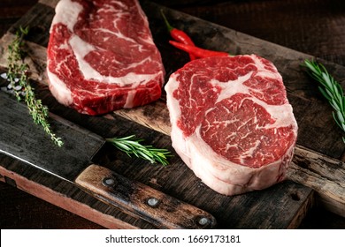 Carne de buey costillada en un tablero de madera con un corte de carne y condimentos