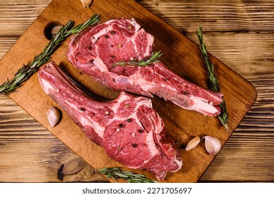 Raw ribeye steak, spices and rosemary on wooden cutting board. Top view - Powered by Shutterstock