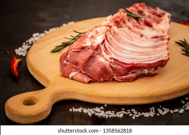 Raw ribs meat with herbs, salt, spices and other ingredients on a wooden board. Top flat view.