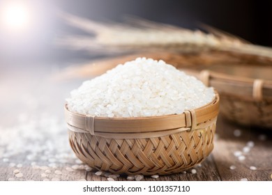 Raw Rice In A Bamboo Basket With Wheat On Wooden Background
