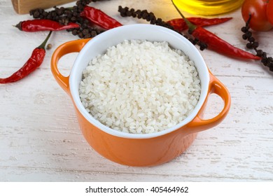 Raw rice in the bowl on wood background