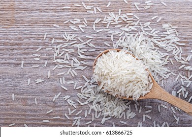 raw rice in a wooden spoon on a wooden background