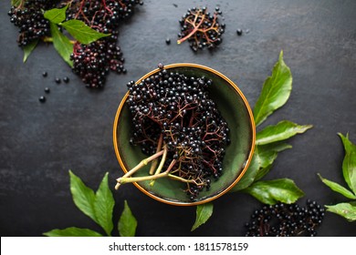 Raw ripe elderberry in a bowl standing on a dark table, top down view - Shutterstock ID 1811578159