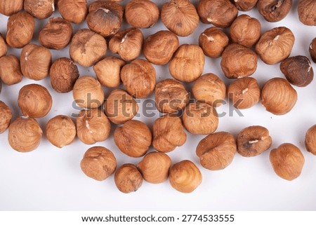 Raw and roasted hazelnuts together. Combination of raw and roasted hazelnuts for culinary uses. Cooking scene featuring variety of raw and toasted hazelnuts in warm hues