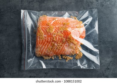 Raw Salmon Fillet With Marinade In Plastic Bag On Grey Background, Top View