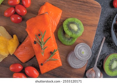 Raw salmon fillets, pepper, kiwi, pineapple and rosemary, wood chopping boards and black cement floors. - Powered by Shutterstock