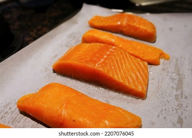Raw salmon fresh fish fillet steak pieces with salt and pepper on the baking paper sheet ready to bake or grill food background close up photo with copy space. Wild caught Atlantic Norwegian fish.
