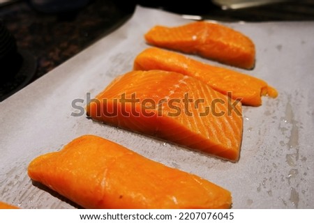 Raw salmon fresh fish fillet steak pieces with salt and pepper on the baking paper sheet ready to bake or grill food background close up photo with copy space. Wild caught Atlantic Norwegian fish.