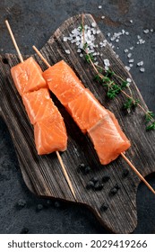 Raw salmon skewers for grilling in the Asian style on wooden board. Seafood barbecue Recipe