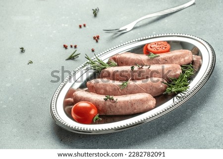 Raw sausages with herbs and spices on a light background. Food recipe background. Close up.