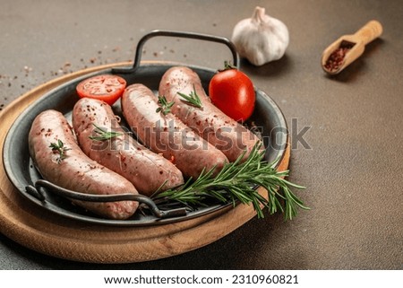 Raw sausages with herbs and spices on a light background. Food recipe background. Close up.