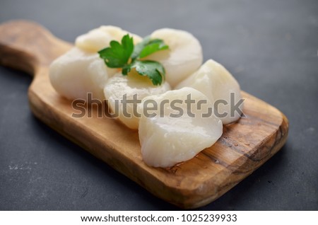 Raw scallops with herbs on frying pan