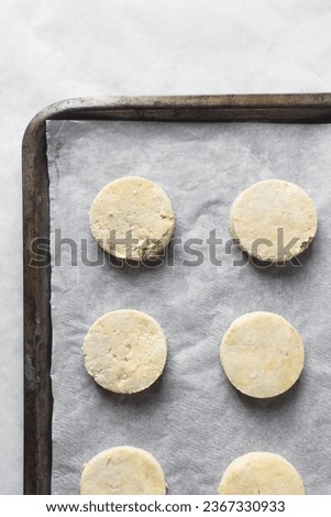 Raw scones on a parchment lined baking sheet, yogurt scones about to be baked, Unbaked buttermilk scones, process of making scones