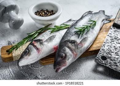 Raw seabass fish on a cutting board with spices, herbs. White background. Top view