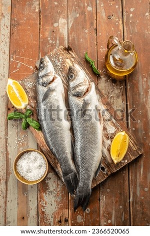 Raw seabass fish on a cutting board with spices, herbs on a wooden background. top view. place for text.