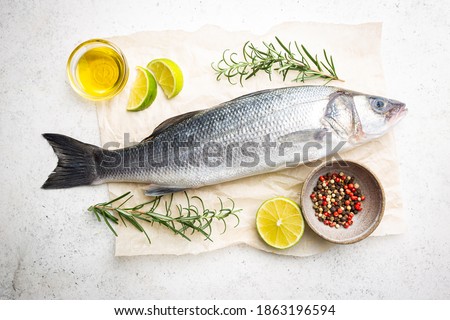 Raw seabass fish with rosemary and spices on white background, top view