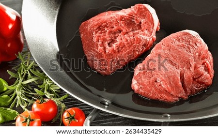 Raw seasoned piece of raw meat prepared for cooking, placed on a kitchen table surrounded by fresh ingredients and herbs  – healthy cooking and lifestyle concept. 