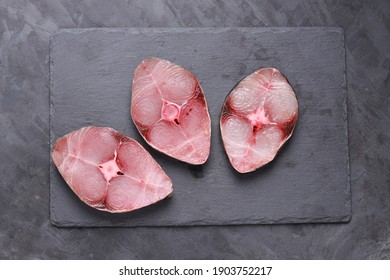 Raw Seer fish or Ayakura ,steaks of seer fish arranged on a graphite slate with grey colour background,isolated  top view.