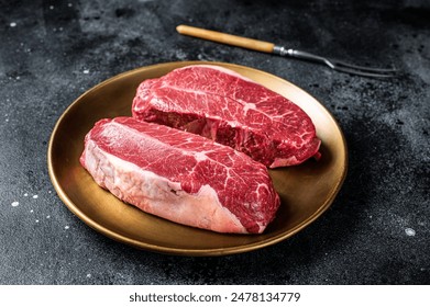 Raw Shoulder Top Blade beef meat steaks on a plate. Black background. Top View. - Powered by Shutterstock