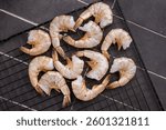 Raw shrimps, headless fresh prawns on a rack. Top view. Black background.