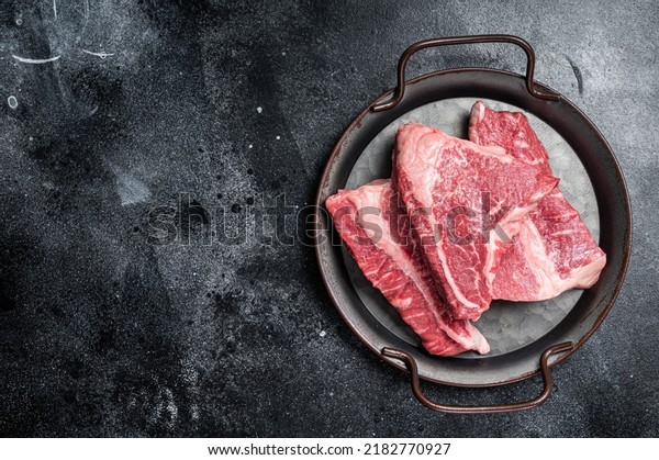 Raw Silverside sirloin\
beef steak cut on butcher tray. Black background. Top view. Copy\
space.