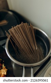 Raw Soba Pasta Is Cooked In A Saucepan On A Gas Stove Close-up. Cooking Soba On The Stove.