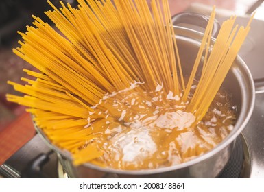 Raw spaghetti is being cooked in boiling water in a kitchen pot. Healthy Italian Food and Cooking concepts.