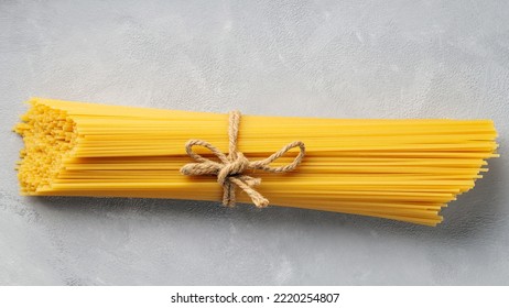 Raw spaghetti tied with twine on a gray background. Uncooked pasta spaghetti on concrete. Top view. Close-up - Powered by Shutterstock