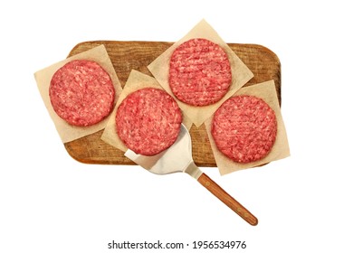 Raw Steak Burgers From Beef And Pork Meat On Cutting Board Isolated On White Background, Overhead View. Uncooked Ground Meat Patties For Grilling. Burgers For BBQ Grill And Spatula, Top View.