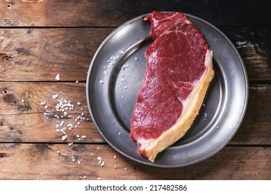 Raw Steak On Vintage Metal Plate Over Old Wooden Table. See Series