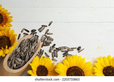 Raw Sunflower Seeds And Flowers On White Wooden Table, Flat Lay. Space For Text