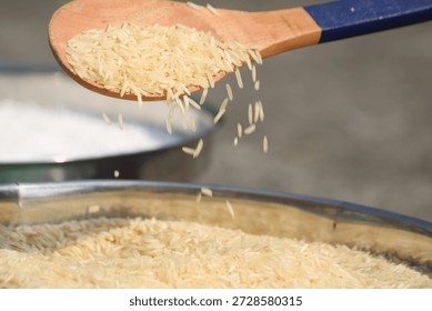 Raw super kernel basmati rice long grain . dropping from up . wooden spoon full with basmati rice . 
