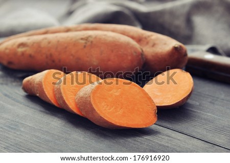 Raw sweet potatoes on wooden background closeup