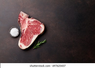 Raw T-bone steak cooking on stone table. Top view with copy space - Shutterstock ID 697625437