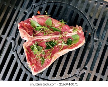 Raw T-bone steak flavored with herbs cooks on the grill