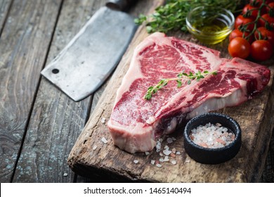 Raw T-bone Steak with fresh herbs and oil on dark wooden background - Powered by Shutterstock