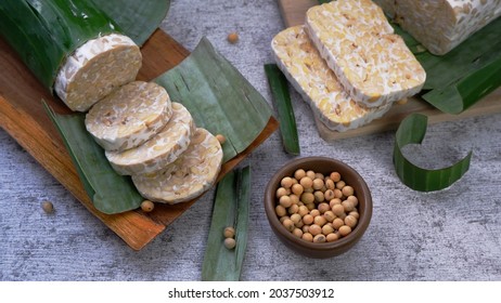 Raw tempeh or tempe mentah.  Tempeh slices in wooden plate. Raw soybean seeds in a brown ceramic bowl. Tempe is Fermented Soy Product Originally from Indonesia.