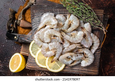 Raw tiger white shrimp prawn on board with herbs. Dark background. Top view.