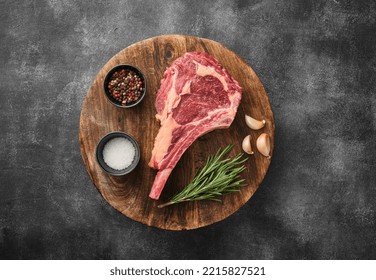 Raw Tomahawk steak on wooden board with spices for grilling, grey background - Powered by Shutterstock