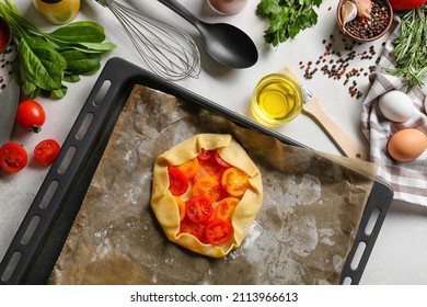 Raw tomato galette in baking tray on table - Shutterstock ID 2113966613