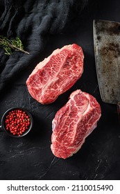 Raw  top blade flat Iron beef cut organic meat ner butcher meat clever knife for bbw or gtrill  over black stone background top view vertical