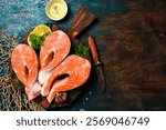 Raw trout steaks seasoned with lime juice, salt and pepper, on a wooden cutting board. Rustic style.