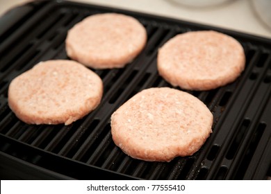 Raw Turkey Burgers Cooking On An Indoor Grill.