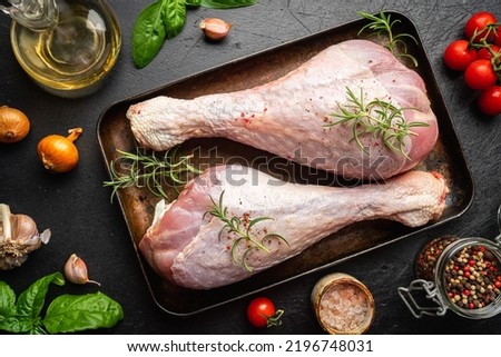 Raw turkey thigh with spices on a dark board, top view